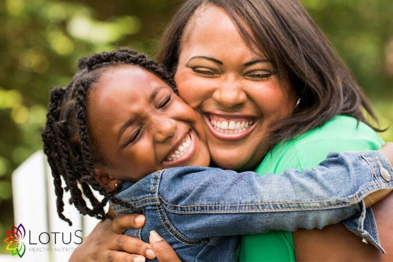 Mother and daughter smiling together outdoors, representing confidence, connection and positive body image.