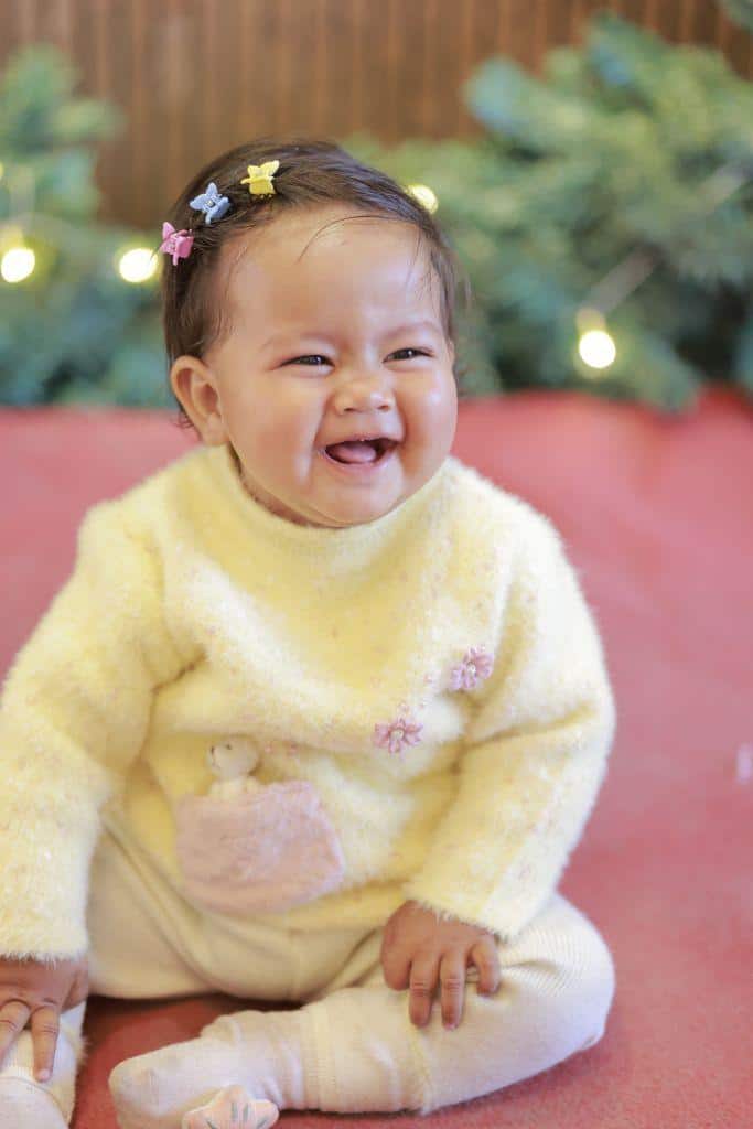 Cute baby girl with hair clips smiling joyfully outdoors in India. Perfect for cheerful child lifestyle themes.